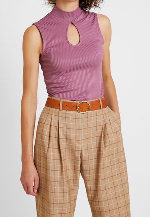 Top mauve sans manches ajusté et côtelé avec un col haut et un détail en trou de serrure, associé à un pantalon à carreaux beige taille haute et une ceinture marron.