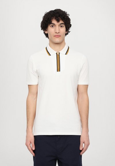 Polo shirt blanc à manches courtes avec un col zippé, arborant une rayure d'accent jaune et marine et une finition texturée.