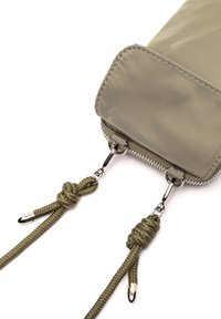 Kakhi nylon maišelis su lygiu paviršiumi, su užsegimu per užtrauktuką ir dviem nuleidžiamais kordais su metaliniais antgaliais patogiam naudojimui.