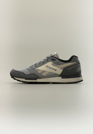 Baskets Reebok gris et beige avec semelle noire, lacets et logo sur le côté, vues de profil sur un fond clair uni.