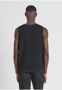 Top in maglia nera senza maniche con un motivo testurizzato, caratterizzato da un collo rotondo e un orlo dritto, visto da dietro.