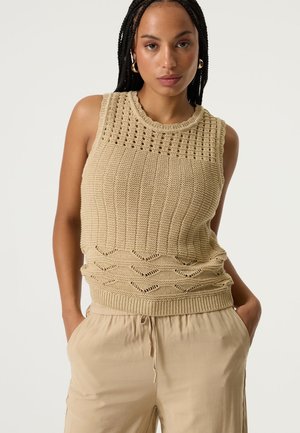 Top smanicato beige in maglia con motivo a trama, scollo tondo e orlo a coste con dettaglio a zigzag sul fondo.