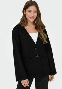 Blazer noir surdimensionné avec col en V, deux boutons et deux poches avant. Confectionné dans un tissu doux à la texture lisse.