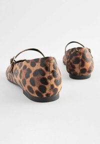 Ballerines à imprimé léopard avec une texture douce, bout arrondi, bride à la cheville et semelle en caoutchouc noir ; motif tacheté dans des nuances de marron et de noir.