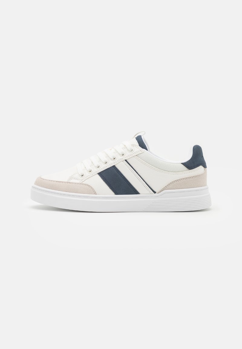 Weiße Sneakers mit marineblauen Streifen und beigen Akzenten. Glattes Lederobermaterial mit strukturiertem Wildleder. Gummisohle, runde Zehenform und Schnürdesign.