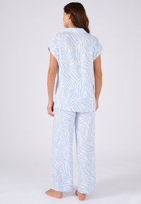 Ensemble de pyjama à rayures bleues et blanches comprenant un haut à manches courtes et un pantalon à jambes larges, fabriqué en tissu doux et léger.