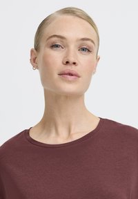 Bordeaux T-Shirt mit rundem Ausschnitt und kurzen Ärmeln. Glatte Textur und minimalistisches Design, ohne Muster oder Akzente.