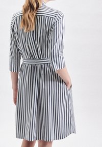 Striped dress in navy and white, made from cotton. Features a belted waist, three-quarter sleeves, and side pockets.