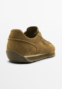Brune ruskind sneakers med lav profil, der har en tekstureret overflade, gummisål og minimalistisk snøredesign. Accenter i beige.
