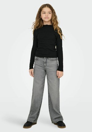 Svart ribbad långärmad topp med skårad halsringning, kombinerad med löst sittande grå jeans. Svarta sneakers fullbordar outfiten.