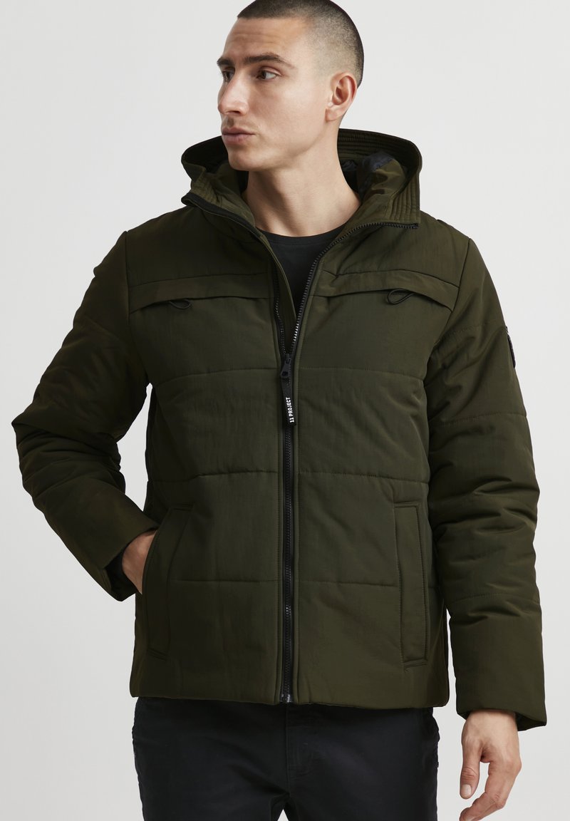 Green puffer jacket featuring a hood, zip closure, and front pockets with a quilted design. Soft texture; lightweight and warm appearance.