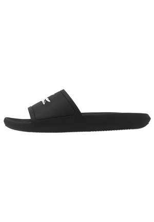 Czarny sandał typu slip-on z teksturowanym paskiem i białym, przeszywanym logo, płaska podeszwa, widok z boku na białym tle.