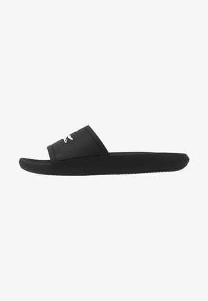 Czarny sandał typu slip-on z teksturowanym paskiem i białym, przeszywanym logo, płaska podeszwa, widok z boku na białym tle.