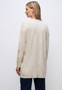 Ljusbeige långärmad tröja med avslappnad passform, ribbade muddarna och nederkant. Mjuk textur med rak design baktill.