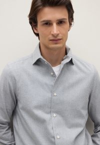 Chemise boutonnée à carreaux bleu clair, en coton, avec un col classique et des boutons blancs. Texture lisse, design décontracté.