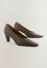 Brown, woven-textured high heels with a pointed toe and a block heel. Smooth interior lining, minimalistic design.