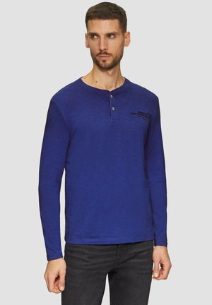 Langarm-Henley-Shirt in Blau mit strukturierter Oberfläche, ausgestattet mit einem Knopfkraagen und dezentem schwarzen Text auf der Brust.