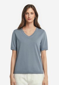 Ljusblå V-ringad t-shirt med korta ärmar, tillverkad av mjukt tyg; har ett ribbat nacke och ärmslut för en strukturerad look.