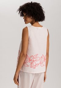 Top sin mangas de color rosa con bordado floral en un brillante coral alrededor del dobladillo. Hecho de una tela ligera, con cuello redondo y ajuste relajado.