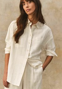 Wit gestreept button-up shirt met opgerolde mouwen, met twee borstzakken en een lichte, gestructureerde stof.