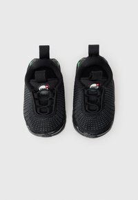 Ζευγάρι μαύρων αθλητικών παπουτσιών για παιδιά με υφή πλέγματος, με λαβές στην πίσω πλευρά και λευκό λογότυπο Nike Air στη γλώσσα, τοποθετημένα το ένα δίπλα στο άλλο σε λευκό φόντο.