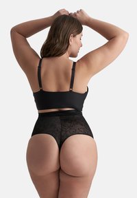 Zwart lingeriesetje met een eenvoudige bralette met verstelbare bandjes en hoge kanten slipjes, die bloemmotieven en transparante textuur laten zien.