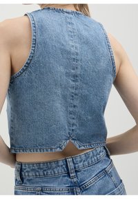 Denimkort topp med hög halsringning, ärmlös design, ljusblå färg och en delad bakseam, ihopparad med högmidjade denimshorts.