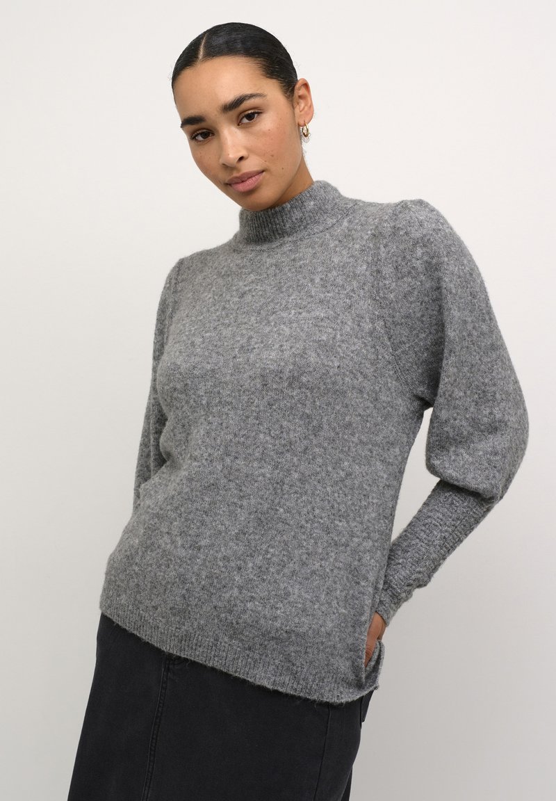Sivi pleteni pulover s visokim ovratnikom, teksturiranom završnom obradom i nabranim rukavima. Ima opušteni kroj i bočne džepove. Materijal izgleda mekano.