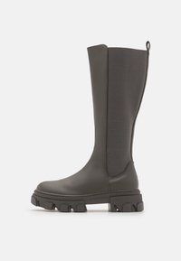 Botas de gris oscuro hasta la rodilla, hechas de un material suave, con un panel de tejido texturizado y una suela de goma gruesa con un diseño de relieve pronunciado.