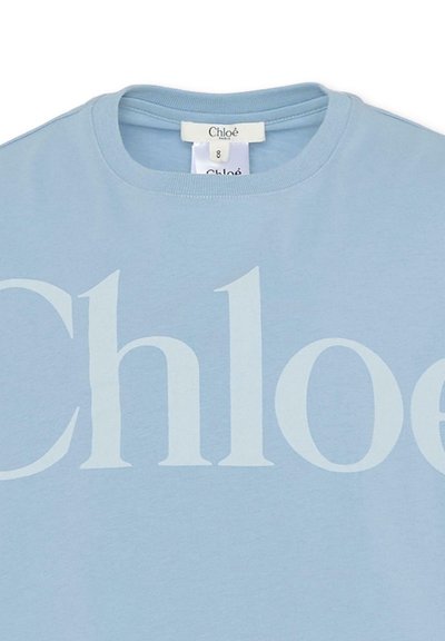 Jasnoniebieska bawełniana koszulka z dużym, jasnoszarym napisem „Chloé” na przodzie. Okrągły dekolt z detalami szwów.