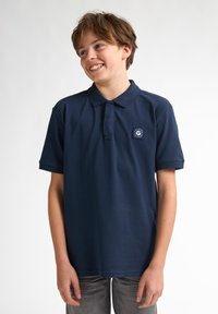 Marinblå polo-shirt i bomull, med en vikbar krage, korta ärmar och en liten logotyp-patch på vänster bröst.