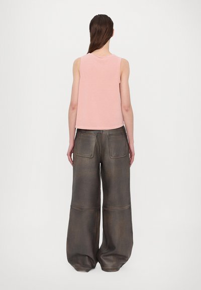 Top sin mangas de color rosa claro combinado con pantalones anchos de pierna amplia en marrón oscuro, sueltos, que cuentan con dos bolsillos traseros y una textura suave.