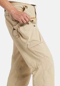 Beige cargobyxor med strukturfinish, som har ett elastiskt midjeband, en sidoficka och justerbara snören för en säker passform.