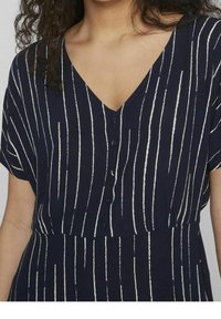 Merenkblue-mekko, jossa on pystysuuntaiset valkoiset raidat, lyhyet hihat, V-kaula-aukko ja napitettavat etuosat. Pehmeä kangas ja rento istuvuus.