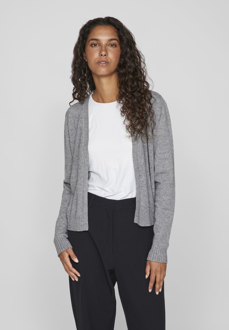 Grijze cardigan van zacht materiaal, met een open voorkant, ribbelmanchetten en zoom, gedragen over een wit shirt en zwarte broek. Glad textuur met een casual pasvorm.
