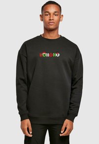Black sweatshirt featuring "HOHOHO" text in red, green, and white with festive accents like Santa hats and reindeer. Casual fit with ribbed cuffs.