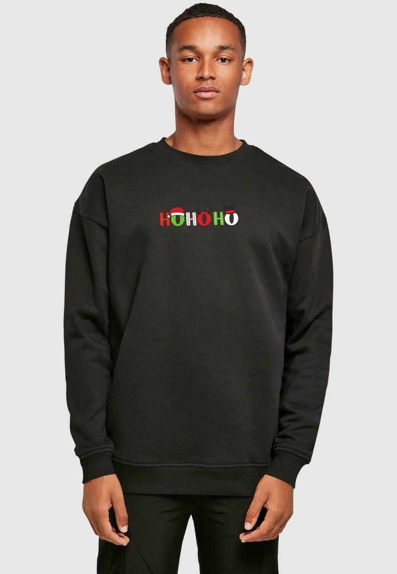 Black sweatshirt featuring "HOHOHO" text in red, green, and white with festive accents like Santa hats and reindeer. Casual fit with ribbed cuffs.