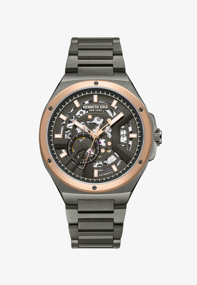 Automatisk klocka med en svart skelettskiva och roséguldfärger, en klocka i rostfritt stål och armband samt vinklade timmarkörer.