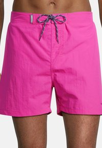 Shorts de bain roses avec une finition texturée, taille à cordon de serrage avec des accents gris et une étiquette logo discrète sur la ceinture.