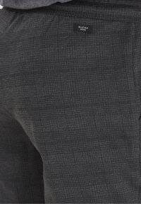 Pantaloni neri a quadri da uomo con una texture morbida, vita elasticizzata e una piccola etichetta "BLEND DENIM" sulla tasca posteriore.