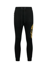 Zwarte joggingbroek van zachte stof, met een slanke pasvorm, elastische tailleband en een gouden sierlijk patroon aan de rechterkant.