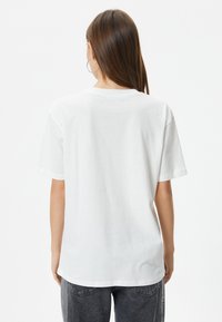 Løs pasform hvid bomulds t-shirt med korte ærmer, rund hals og lige kant. Stoffet ser blødt ud med en glat tekstur.