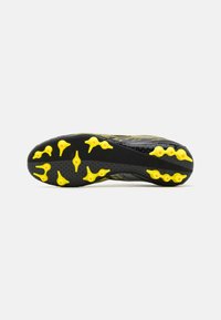 Semelle de chaussure de sport noire et jaune avec des crampons de traction proéminents et une surface noire texturée. Possède un design léger.