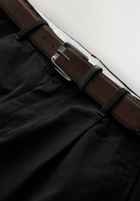 Sorte stofbukser med et brunt læderbælte, der har en sølvmetalknap og syede detaljer langs taljen.