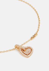 Collar en tono dorado con un colgante en forma de corazón adornado con cristales transparentes, unido por una delicada cadena.
