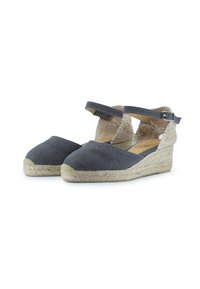 Espadrilles de tela gris con un tacón trenzado en tono marrón, tira en el tobillo y suelas de yute. El diseño presenta una textura suave y una puntera redondeada.