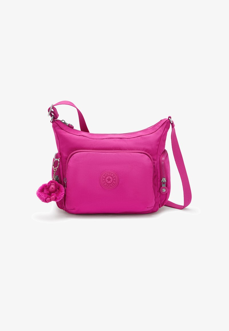 Pink nylon crossbody bag with a zippered front pocket, adjustable strap, and furry monkey keychain. Features a round logo patch.