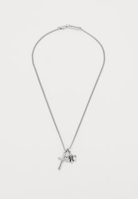 Sølvkjede med kors og fleur-de-lis anheng på hvit bakgrunn, med en liten "ICON" tag nær l�åsen.