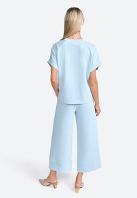 Light blue, relaxed-fit top with short sleeves and crew neckline, paired with matching wide-leg pants. Smooth fabric with a soft texture.
