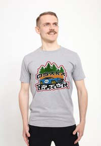 Camiseta de algodón gris con un gráfico que presenta árboles verdes y un coche azul, acentuado con texto y formas coloridas en negrita.